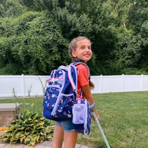 Child wearing a backpack while walking outdoors, representing adaptive backpack options for everyday use.