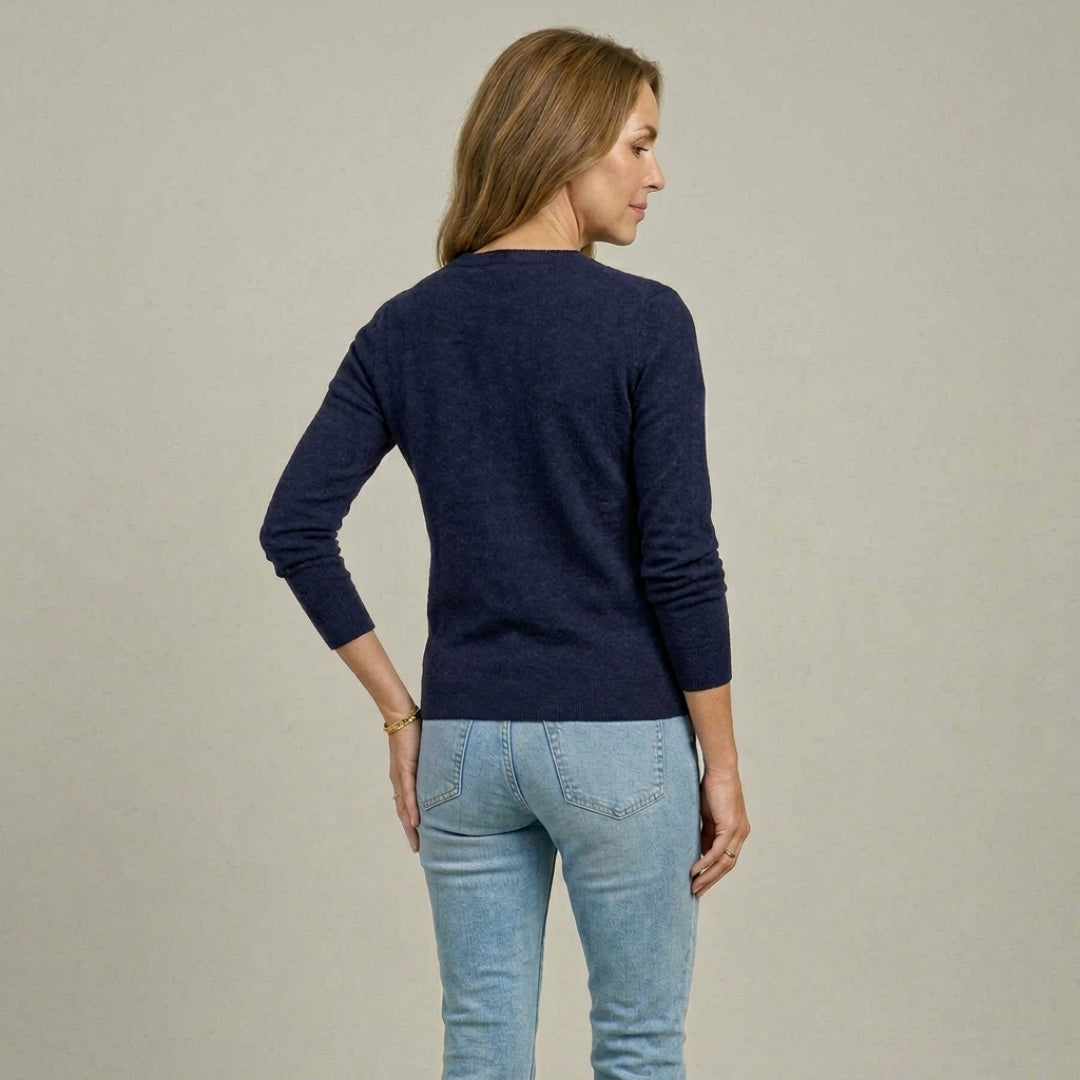 Woman wearing MagnaReady navy magnetic knit cardigan and light blue jeans, shown from behind, against a beige background.