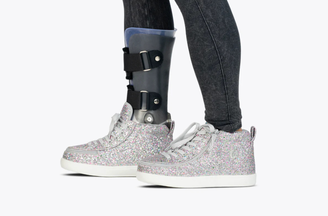 Person wearing silver sparkle BILLY high top adaptive sneakers with an AFO brace
