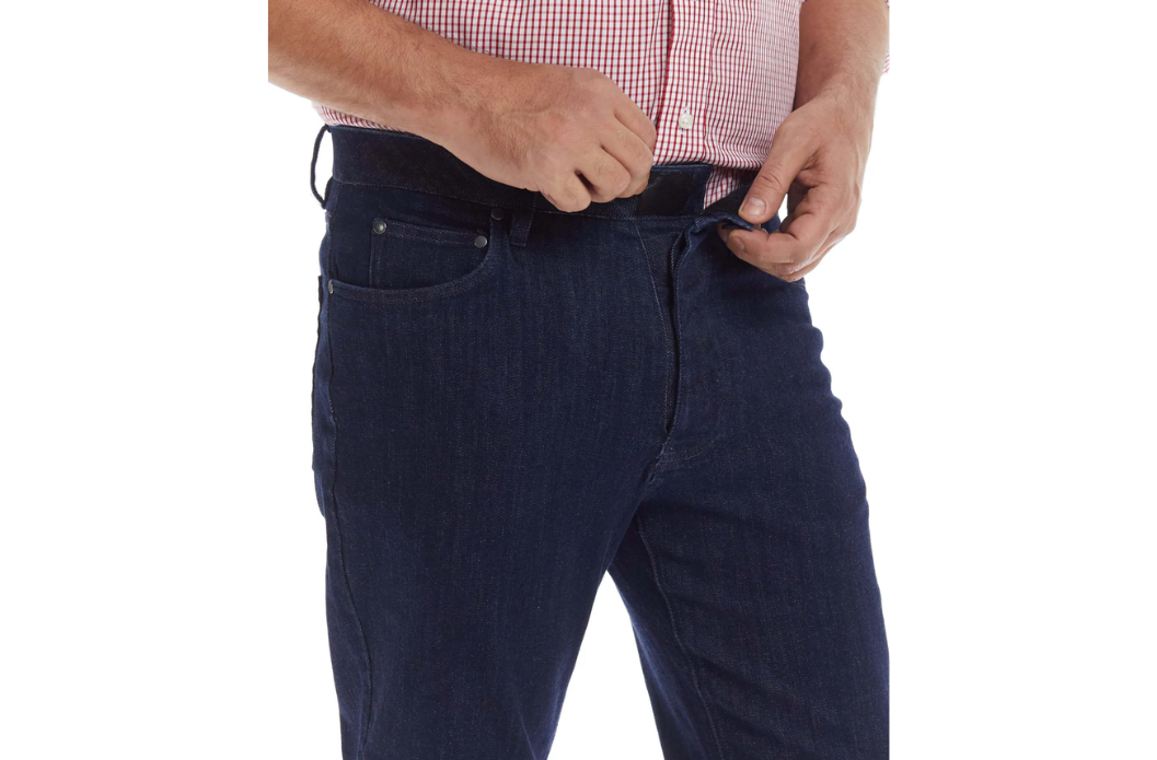 Man closing the magnetic fly on MagnaReady adaptive jeans while wearing a plaid shirt.