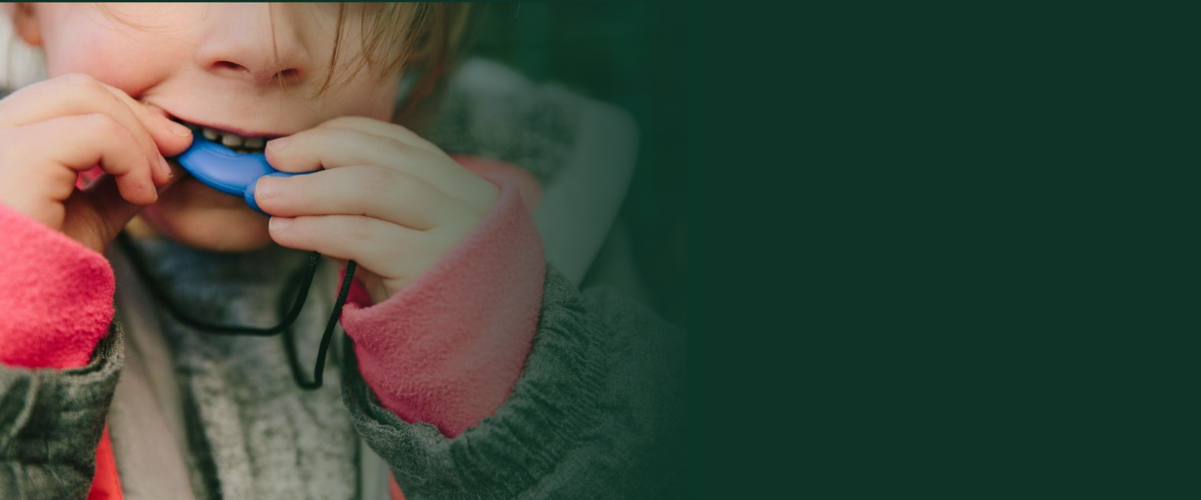 Young child chewing on a blue sensory chew necklace pendant, close-up
