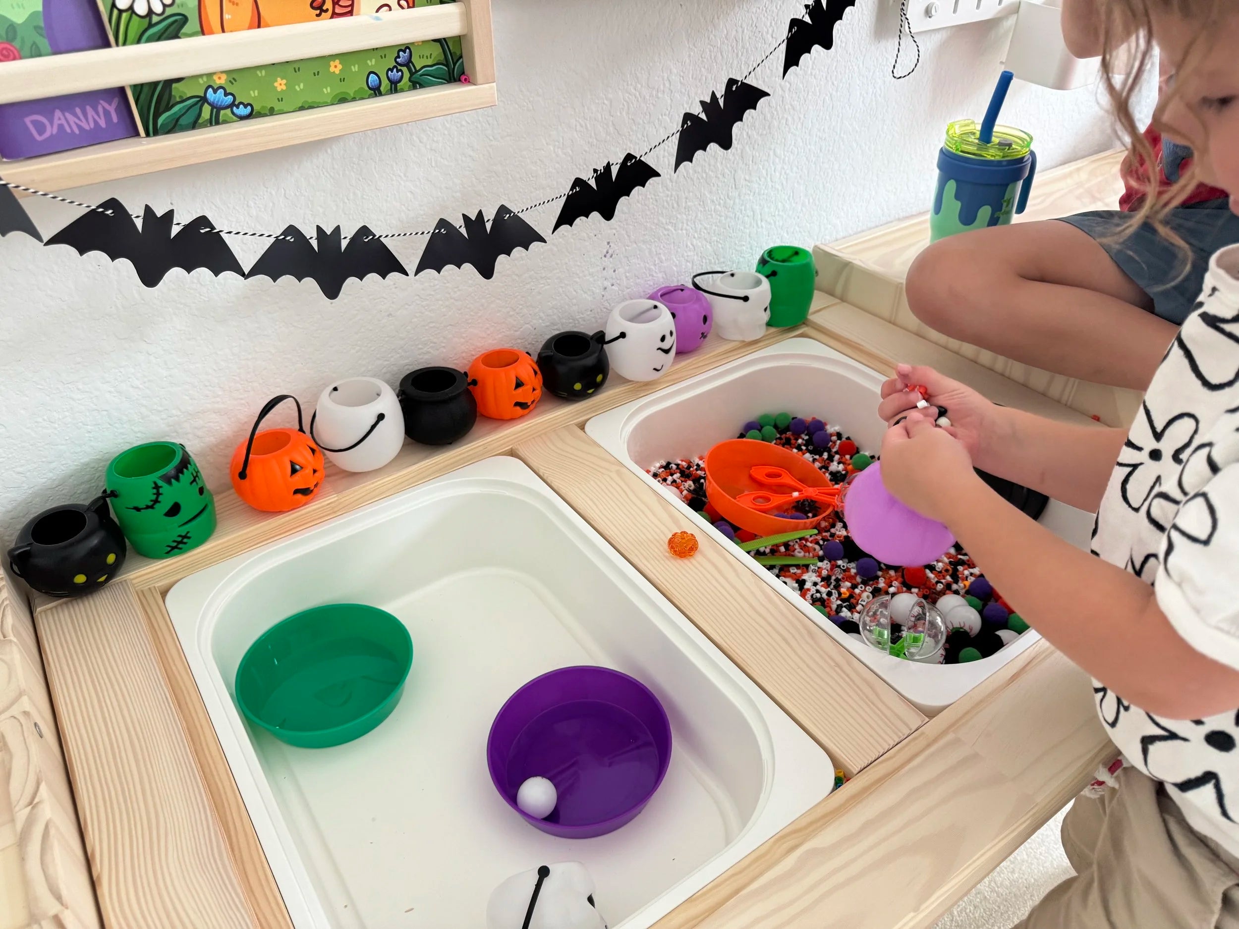 Child playing with a Halloween sensory bin with scoops and textured materials