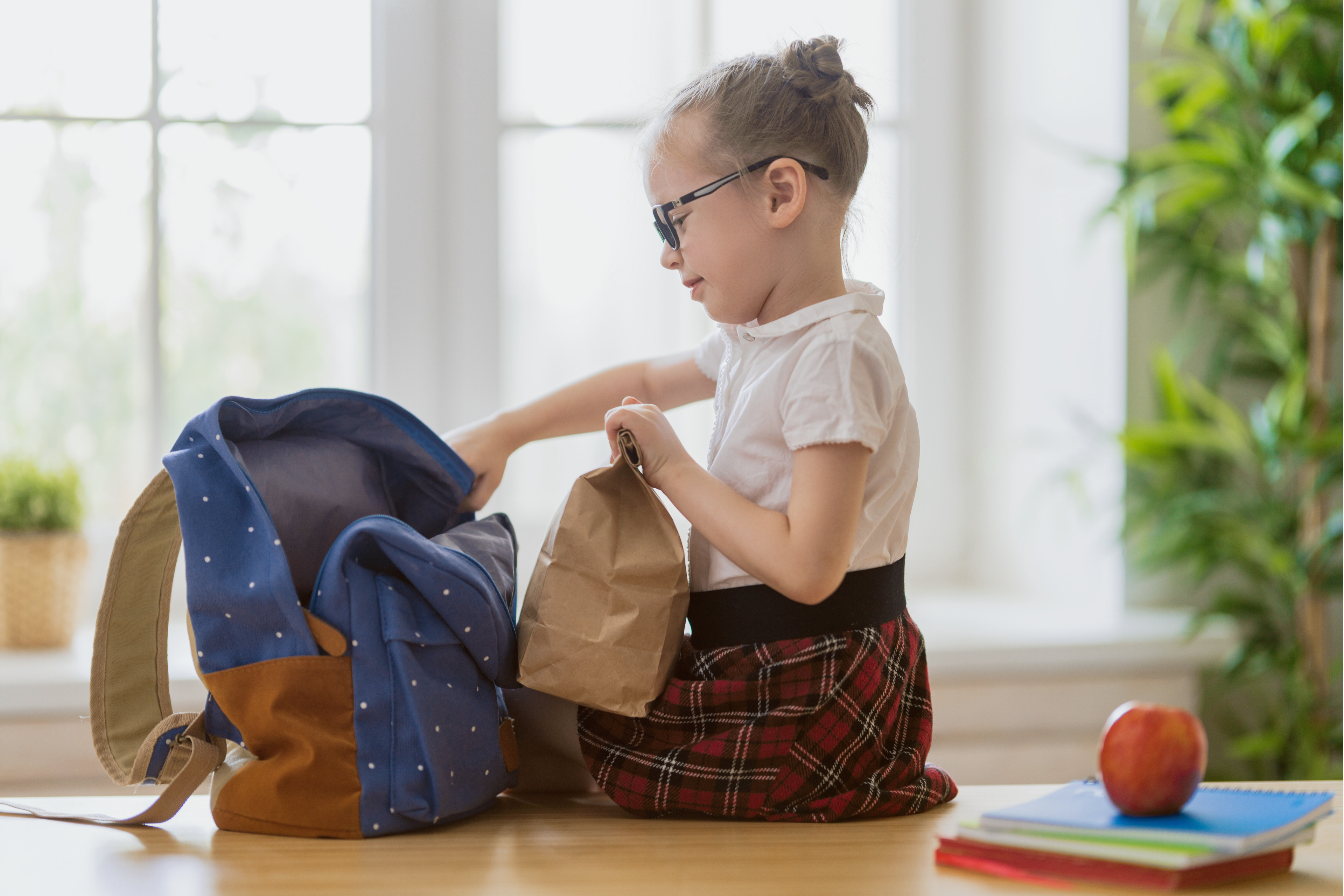 Child packing a backpack at home as part of a daily routine.