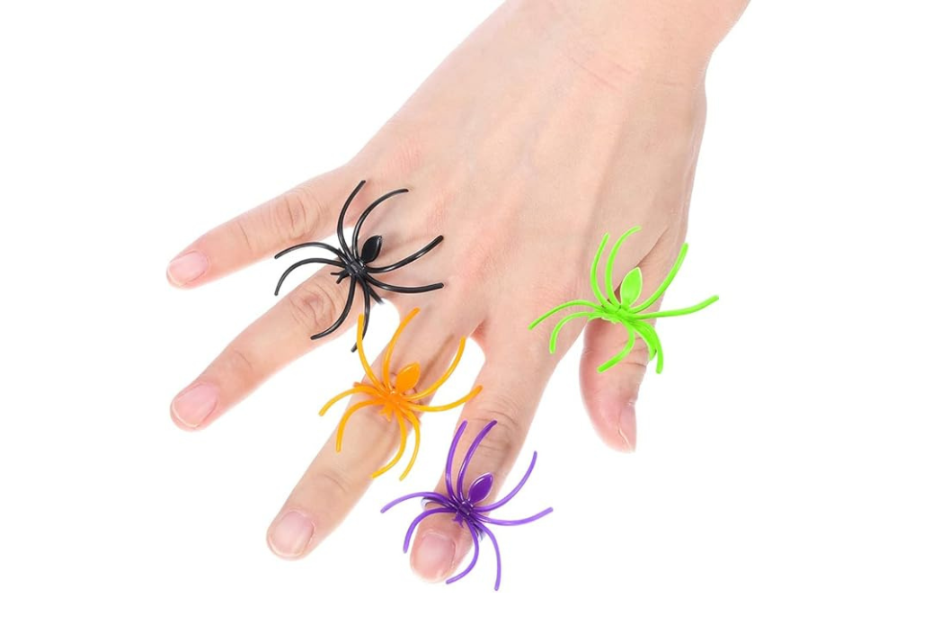 Black, orange, purple, and green plastic spider rings displayed on a hand
