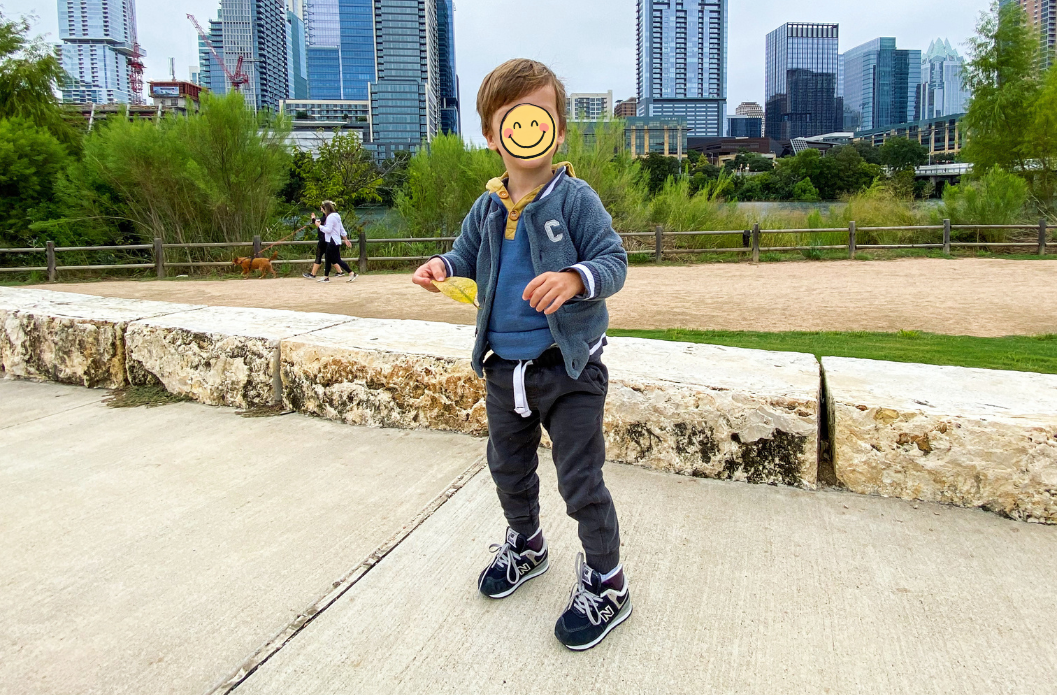 Child playing along a path in a city in New Balance 574 shoes, demonstrating durable everyday school shoes for active kids.