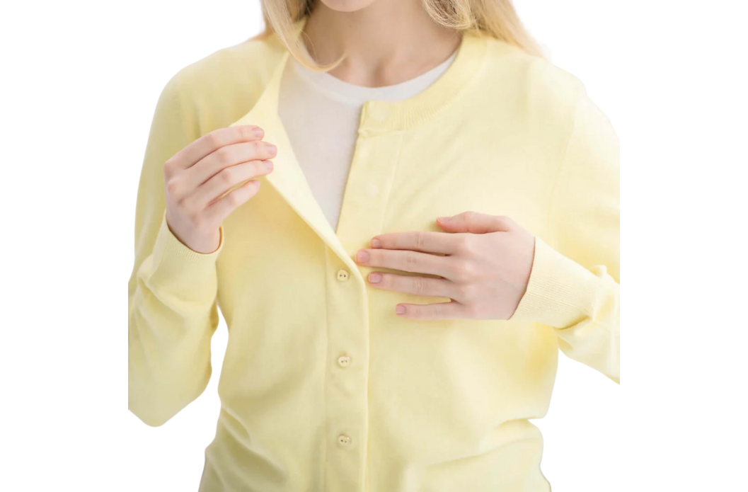 Woman opening a yellow MagnaReady magnetic cardigan with one hand.