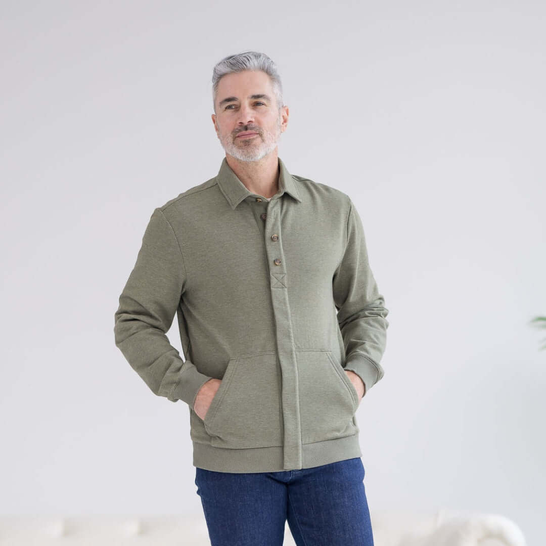 Man wearing MagnaReady heathered olive magnetic sweatshirt with hands in pockets against a white background.