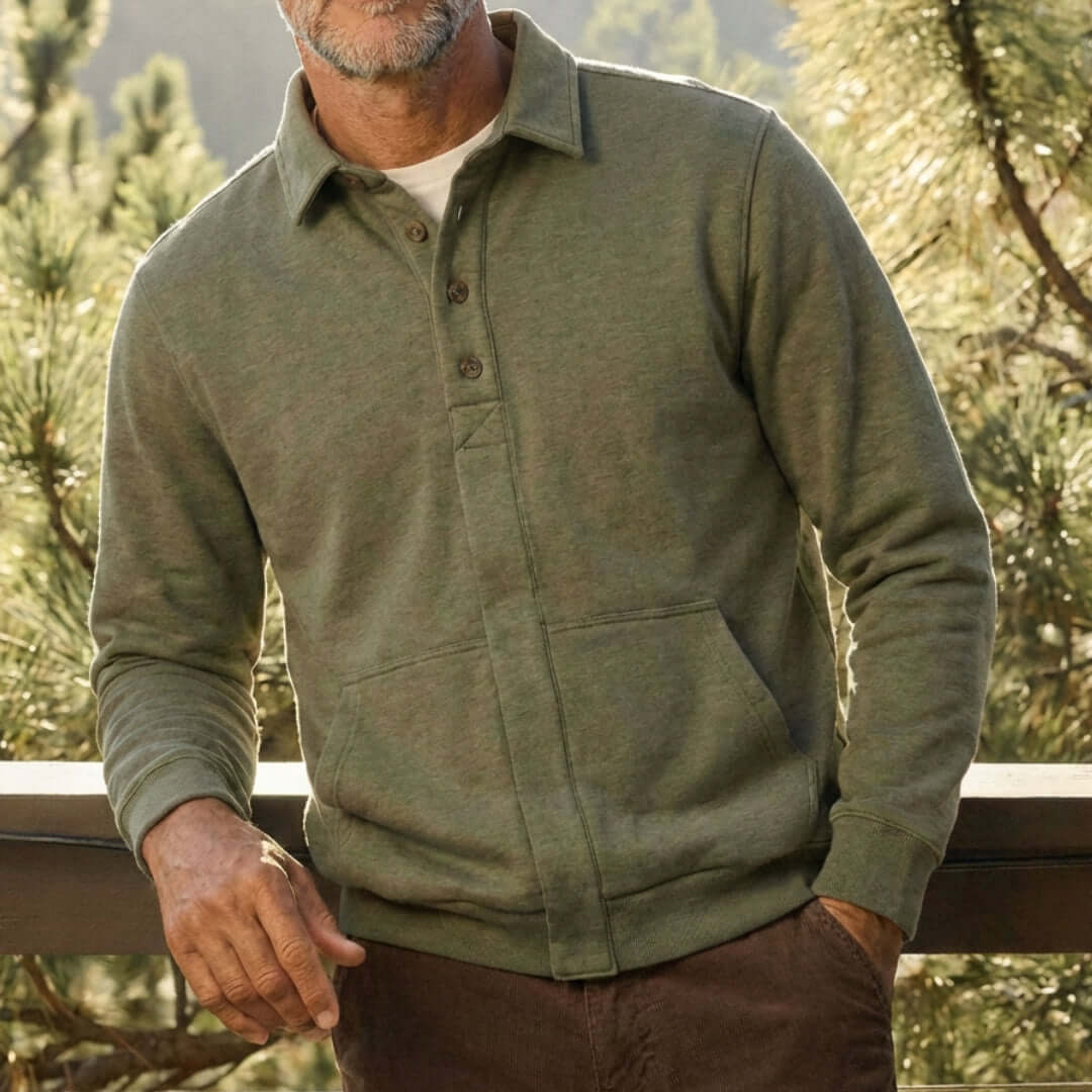 A man wearing MagnaReady heathered olive magnetic front sweatshirt with a collar and front pockets, photographed outdoors against a blurred forest background.