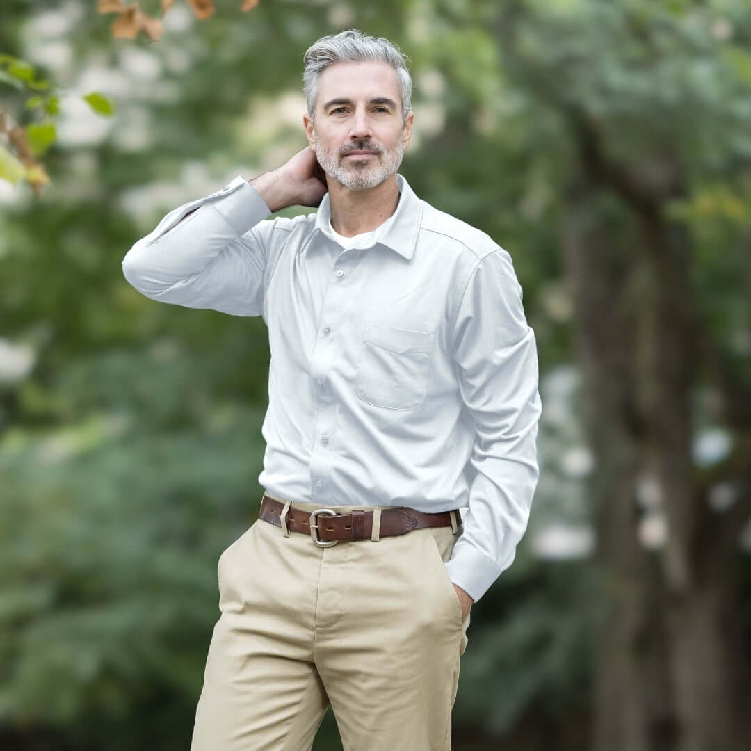 Man wearing MagnaReady white magnetic cooling shirt and khaki pants standing outdoors with trees in the background.
