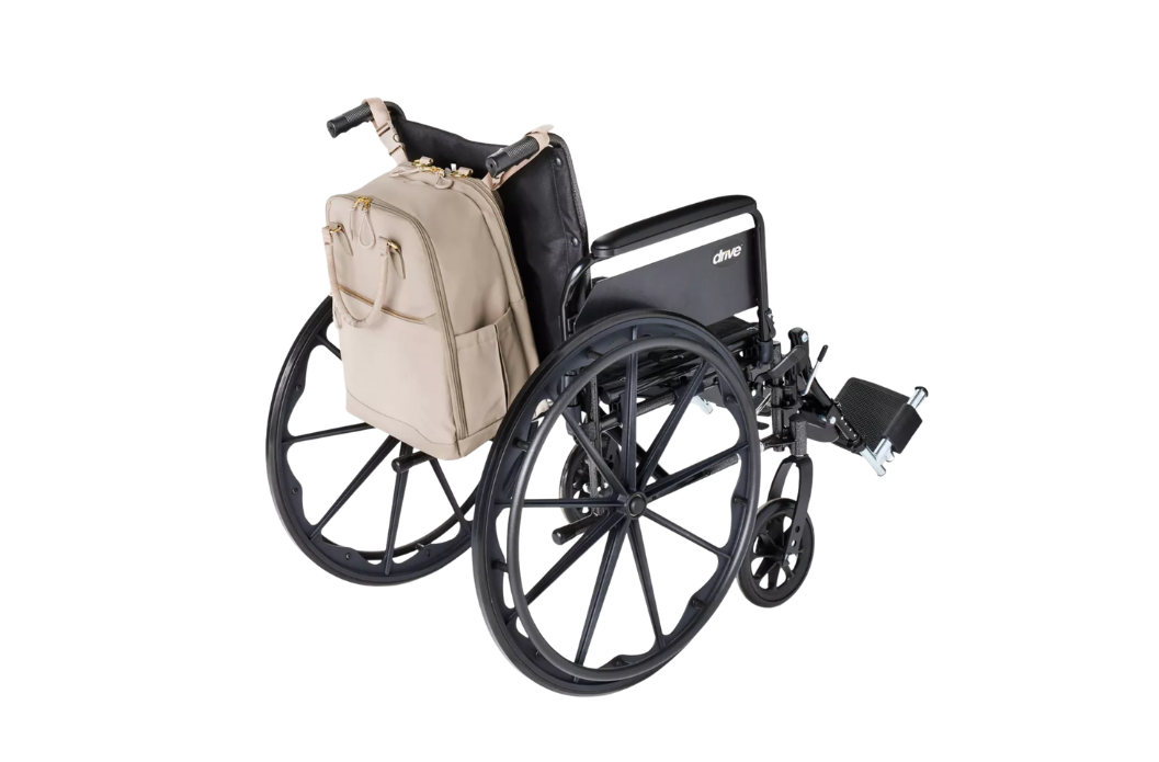 Tan structured laptop backpack mounted to the push handles of a Drive medical wheelchair, rear view