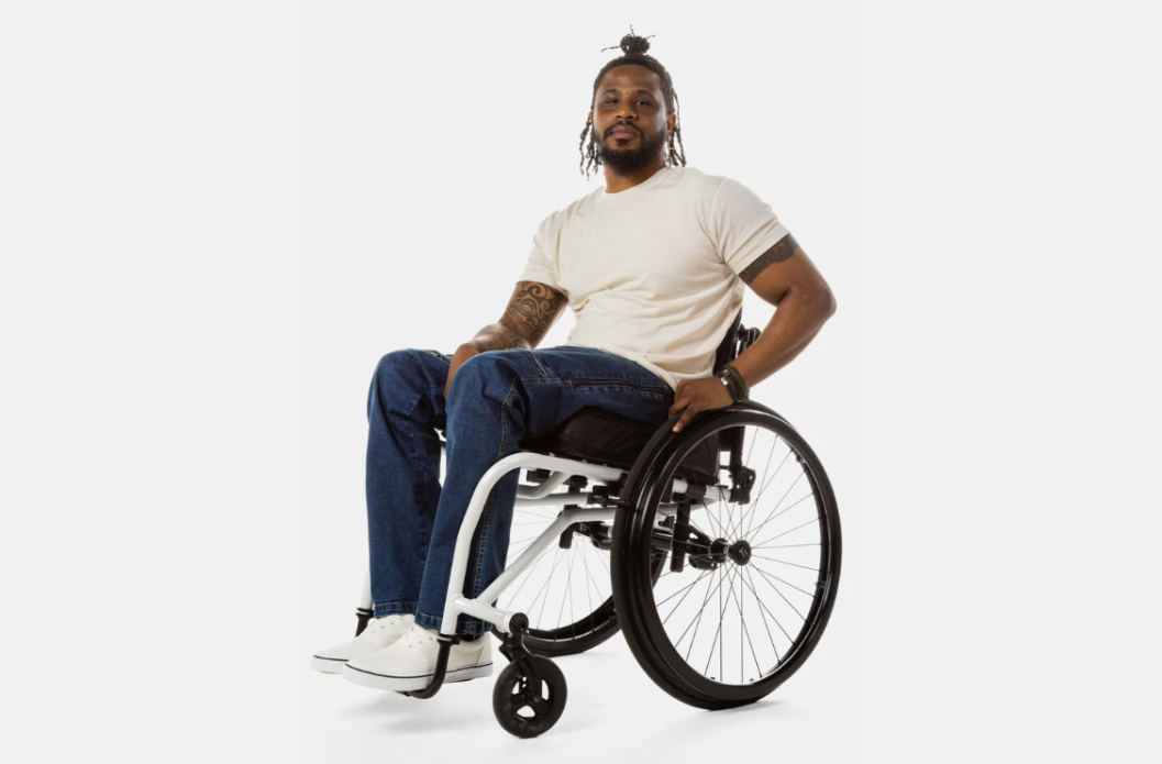 Man seated in a manual wheelchair wearing No Limbits adaptive jeans designed for seated wear, front view