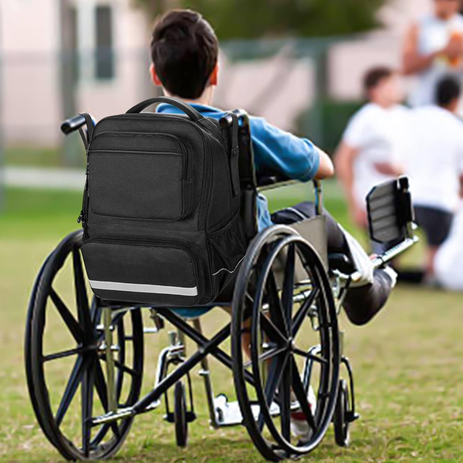 An all black backpack mounted on the back of a wheelchair outdoors.