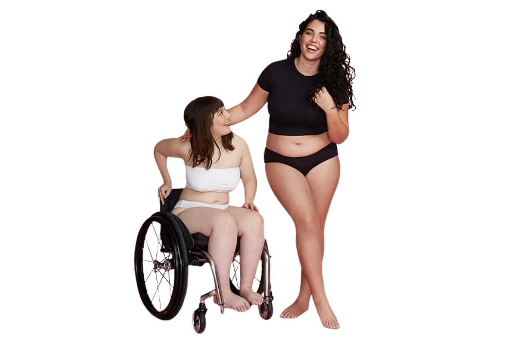 Two women, one using a wheelchair and the other standing, wearing Slick Chicks adaptive underwear.
