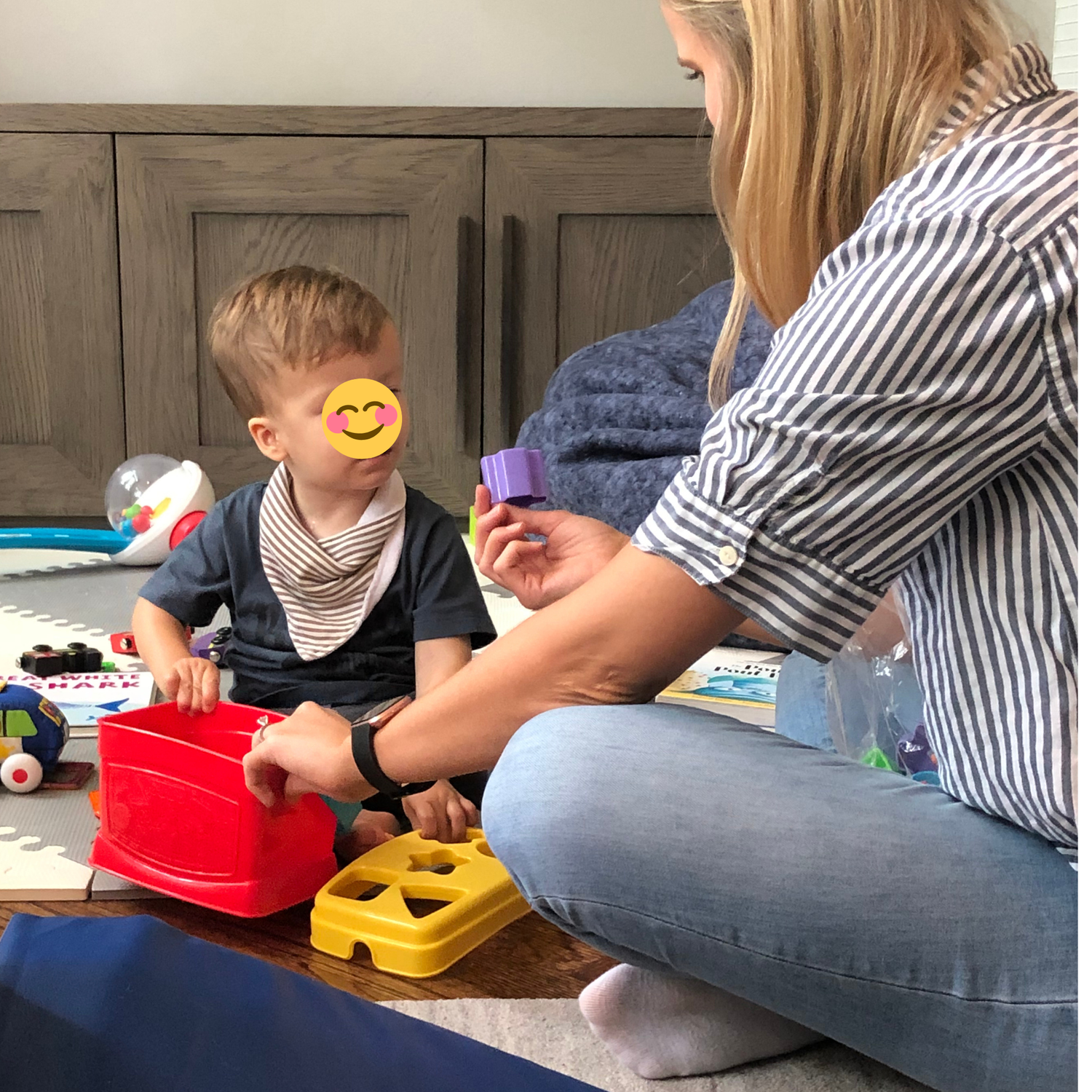 Speech therapist sitting on the floor talking with a young child during play.