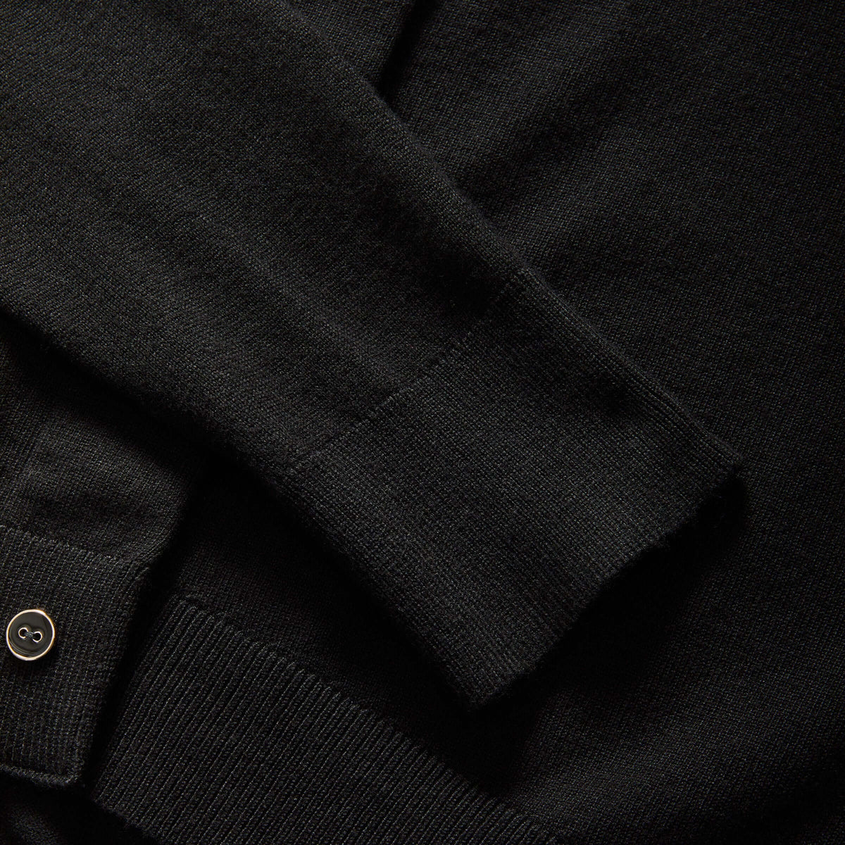 Close-up of MagnaReady black knit cardigan sleeve and cuff detail.